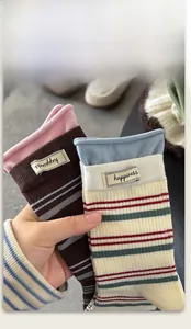 Details von hochelastischen Rippbündchen und Stoffetiketten an gestreiften Socken