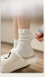 Detail showing the elastic cuff and egg label on white cable knit cotton socks