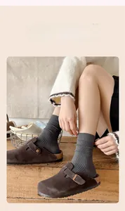 Detail of dark brown suede mule slippers with cork sole and grey ribbed crew socks