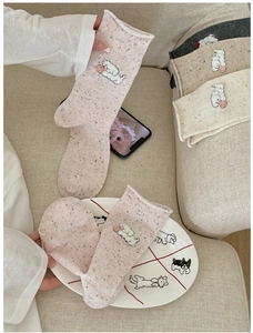 Close-up of knit crew socks with cute cartoon puppy flocking and colorful speckled yarn