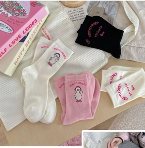 Detailed flat lay of pink, white and black cotton socks with cute cartoon duck patterns