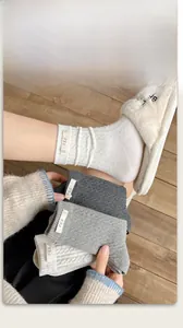 Detail of cable knit crew socks featuring white egg tag on the side and soft cotton texture
