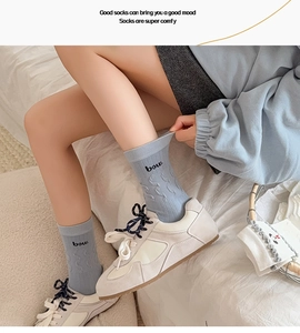 Gros plan de chaussettes en tricot gris bleu avec broderie bow et motifs torsadés