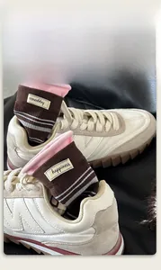 Nahaufnahme brauner Strickstrümpfe mit rosa Bündchen und Happiness-Label in Sneakern