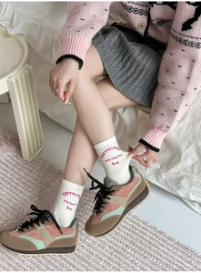 Detail of white cotton crew socks featuring red letters with stylish sneakers and skirt