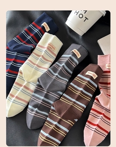 Nahaufnahme von fünf gestreiften Socken-Paaren mit Serendipity-Webetikett auf schwarzem Leder