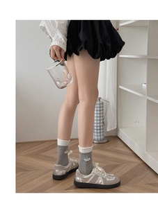 Detail of grey crew socks with cute embroidery paired with silver lace-up platform shoes