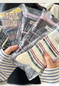Nahaufnahme bunter gestreifter Baumwollsocken mit Buchstaben-Patches in Verpackung