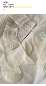 Detail von cremeweißen Socken mit Spitzenkante, Punkten und blauer Schleife in weicher Optik