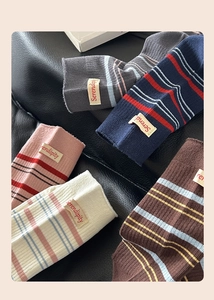 Detailansicht gestreifter Strickstulpen mit Serendipity-Label an gerippten Bündchen