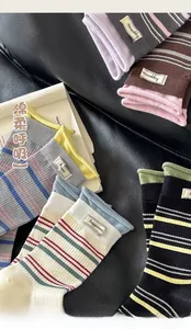 Nahaufnahme bunter gestreifter Baumwollsocken mit Happiness-Label auf Lederhintergrund