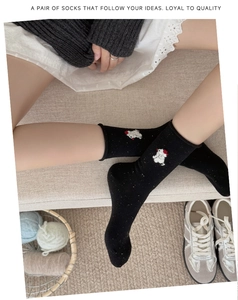 Detail of black cotton socks with colorful flecks and white animal embroidery on the side