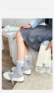 Detail von blau-weißen Wadensocken mit Rüschen und dunkelblauem Schleifendruck-Detail