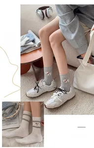 Détail de chaussettes grises mi-mollet avec jacquard chien blanc et nœud rouge mignon