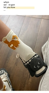 Close-up of white crew socks with orange cat patterns paired with checkered canvas shoes