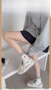 Detail of white sneakers with pearls and grey puppy pattern crew socks on a model