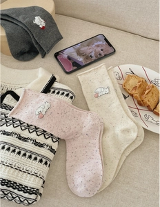 Detail of colorful neps yarn socks featuring fine cartoon dog embroidery in a cozy setting