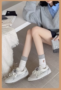 Detailed view of white socks with gray polka dots, dog embroidery and pearl lace sneakers