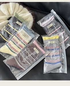 Detail von fünf Paar gestreiften Socken mit Happiness-Labels in Reißverschlusstüten