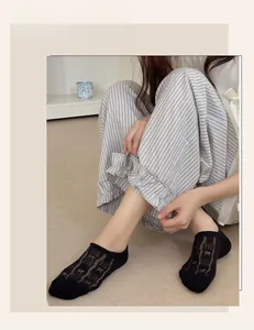 Close-up of black lace mesh invisible socks worn by a model in a cozy home setting