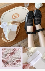 Detailed macro view of sheer hollow-out lace boat socks with silk ribbon bow accents