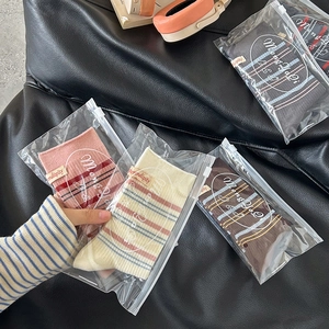 Vier Paar gestreifte Crew-Socken mit Etiketten in hochwertigen Reißverschlussbeuteln