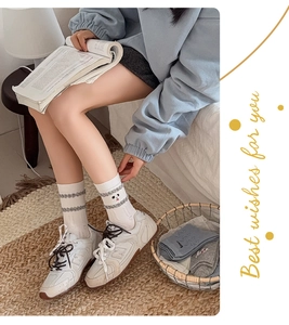 Détail de chaussettes en maille blanche avec broderie cartoon et texture ondulée grise