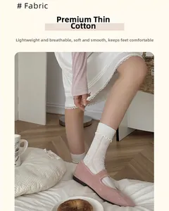 Detailed view of white mesh socks with lace trim and delicate bow patterns on light cotton