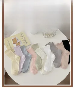Top view of cream colored mesh cotton socks in multiple pastel colors on a white table