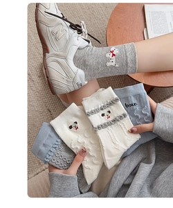 Détail de chaussettes en maille torsadée grise avec broderie chiot et nœud rouge 3D