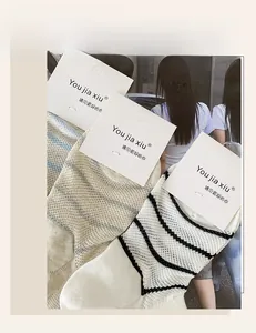 Detail of three pairs of mesh striped and plaid cotton socks with paper packaging cards