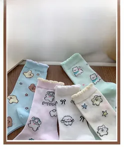 Close-up of pastel cotton socks with cute cartoon puppies and ruffled edges on wood