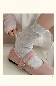 Detail of grey mesh knit socks with wavy ruffled edges and pink Mary Jane shoes