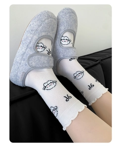 Detail of white ruffled socks with cartoon sheep pattern and blue felt Mary Jane slippers