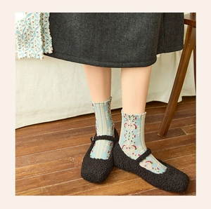 Close-up of vintage floral embossed socks paired with black Mary Jane plush shoes
