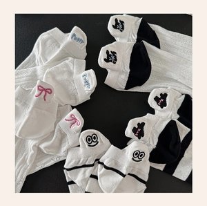 Detailansicht weißer Baumwollsocken mit bunten Tier- und Welpen-Stickereien am Saum