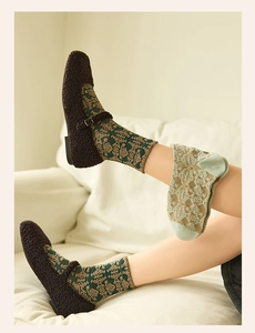 Detailed close-up of dark green crew socks with vintage gold floral jacquard pattern