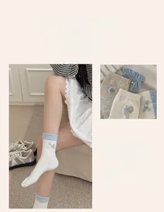 Detail of white crew socks featuring blue polka dot cuffs and sweet ribbon bow accents