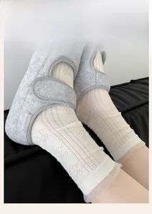 Close-up of white mesh lace socks with intricate hollow patterns and ruffled edges