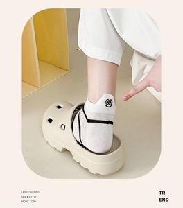 Nahaufnahme weißer Baumwollsocken mit Stickerei und Plateau-Clogs für den Sommer