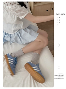 Close-up of retro light blue sneakers with white stripes on a soft white bed sheet