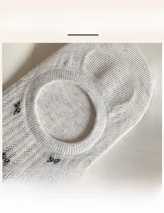 Detail of high-elasticity ribbed cuff on white mesh socks with small black bow patterns