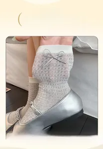 Detail of high-elastic wide cuff on white mesh socks with a silver bow decoration