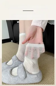Close-up of white mesh lace socks with elastic cuffs and intricate hollow patterns