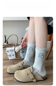 Detail of light green ruffled cuff socks with cute pink cartoon cat patterns