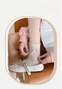 Detail of cream rib-knit mid-calf socks with ruffle trim and pink plaid bow accent
