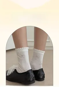 Detail of white mesh socks with brown bow pattern and decorative wavy ruffle cuff