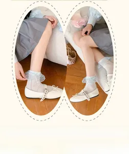Detail von weißen Lolita-Socken mit blauer Spitze und Schleifen auf Mary Jane Schuhen
