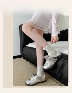Close-up of white lace crew socks with hollow patterns paired with silver metallic sneakers