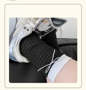 Detail of mesh socks with white trim and silver leather bow in a preppy college style